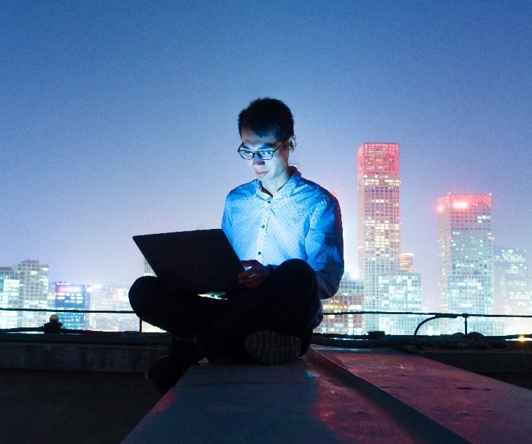 Man on computer, city in the background